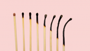 A row of matches on a pink background symbolising burnout